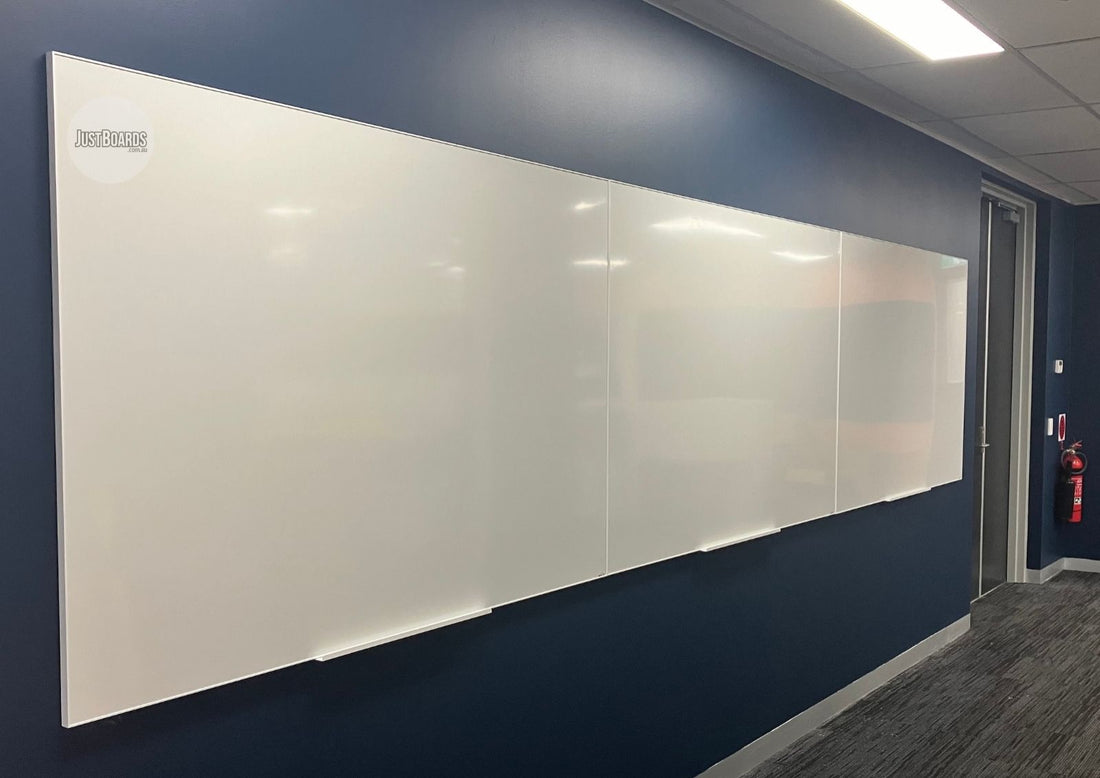 Wide magnetic white glassboard on a navy office wall
