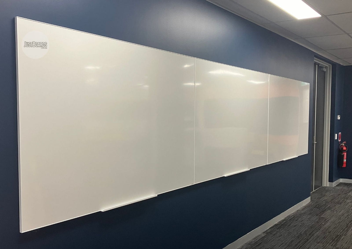 Wide magnetic white glassboard on a navy office wall